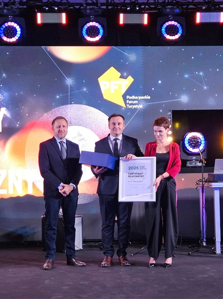 Gala PROT-u - na scenie stoją: Dyrektor POT, Dyrektor MZŁ dr Piotr Szopa oraz Dyrektor Wioletta Rejman. Dr P. Szopa trzyma certyfikat PROT. W tle grafika i logo gali.