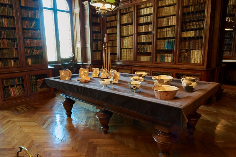 Obiekty z wykopalisk wyeksponowane na zabezpieczonym stole bilardowym. Wnętrze Biblioteki Zamkowej.