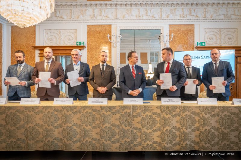 Sala Balowa, za stołem stoi 8 mężczyzn, po podpisaniu porozumienia Dolina Sarmacka