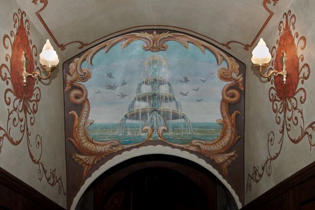 Widok ze schodów prowadzących do Łaźni Zamkowych. Widoczne polichromie przedstawiające fontannę, w tle wody morskie, motywy roślinne